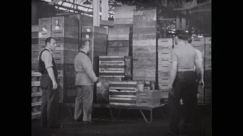1940s: Foreman points to stack of boxes. Men climb boxes and unload materials. 스톡 동영상 230464945
