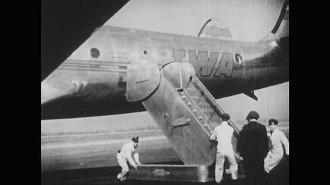 1940s: Ground crew remove steps from plane. Plane starts engine. Man waves at Stock Footage 75165129