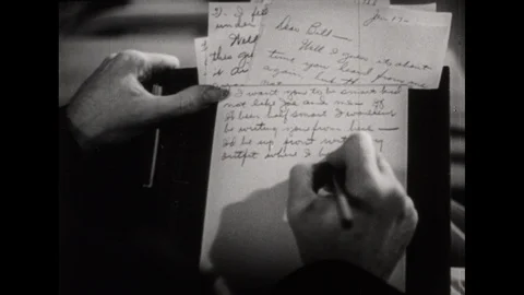 1940s: Hands writing letter. Dissolve, tracking shot, soldier walking through Stockbeeldmateriaal 113946005