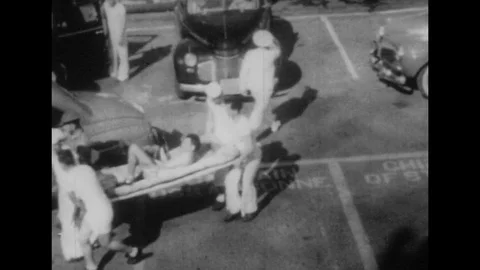 1940s: High angle views, wounded carried on stretcher / Man loads ambulance, pan Video stock 74508421