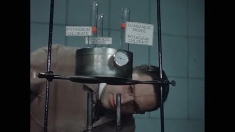1940s: Labeled test tubes in lab equipment, man lights burners under tubes. Stock Footage 172025674
