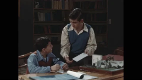 1940s: lady smiles with clapper board. Boys add wall to architectural model of Stock Footage 189945607