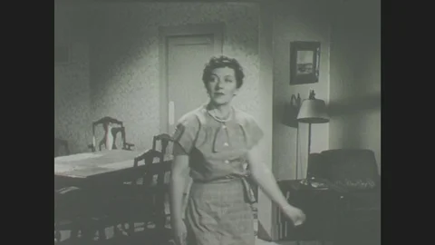 1940s: Lady speaks to girl. Lady lays table. Hand cuts newspaper Stock Footage