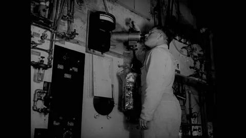 1940s: Man adjusts knobs on factory machinery, looks into viewer into chamber. 库存影片 158441647