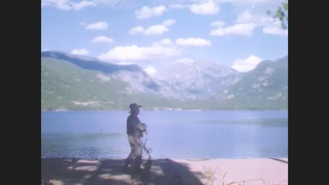 1940s: Man in cowboy attire walks by lake. Man and woman in cowboy attire walk Stock Footage