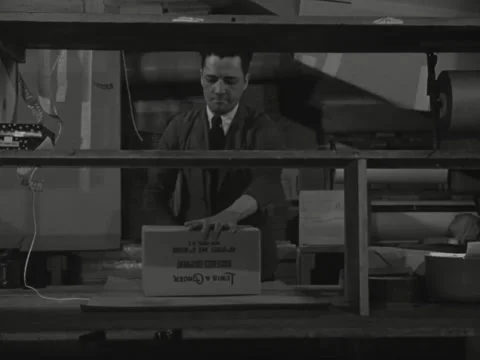 1940s: Man demonstrates process of wrapping box for shipment Video stock 231725779