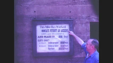 1940s: Man points to sign at mine entrance about days worked without incident. Stock Footage