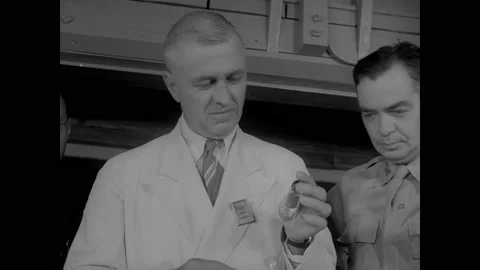 1940s: Man pulls glass jar on string from metal tube on table. Man holds up Stock Footage 158441581