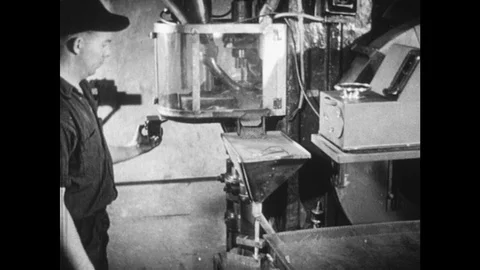 1940s: Man pulls lever on factory machine to press out sample bearings which the Stock Footage 98333339