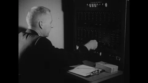 1940s: Man sits in front of console pressing buttons and turning knobs. Man sits 스톡 동영상 118149503