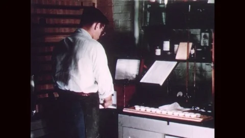 1940s: Man tests soil inside laboratory. Man operates machine and takes notes. Stock Footage 77243217
