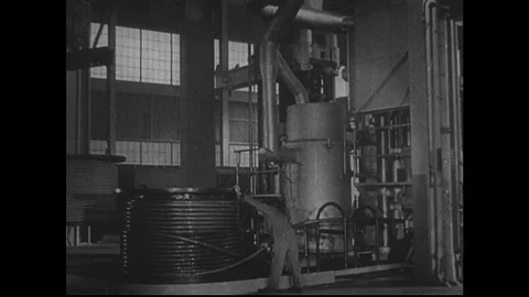 1940s: Man works in engine room. Close up of machine in room. View across valley Stock Footage