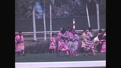 1940s: Men and women in ethnic dress walk around in center of field. Horses race Stock Footage