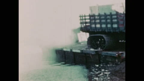 1940s: Men hook trailer full of cargo to tractor, tractor pulls cargo off barge. Stock Footage 154261749