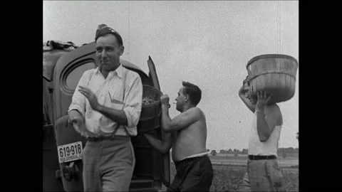 1940s: Men load baskets of beans into truck. Cars pull away from house, people Stock Footage 162327292