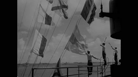 1940s: Men signal with flags on deck of ship. Man flashes spotlight. Stock Footage 159173512