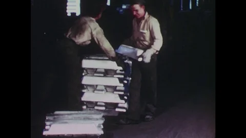 1940s: Men stack metal bars / Machinery in factory / Workers leave factory / Stock Footage 74635366