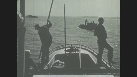 1940s: Men work on boat. Men hold rods in water Stock Footage