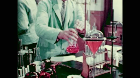 1940s: Men work in lab. Man swirls liquid around in beaker. Man looks at Stock Footage 148502611