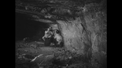 1940s: Men at work in mine shaft push and pull rod out of hole in mine wall. Man Stock Footage 127732608