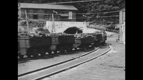 1940s: Mine carts full of coal zoom from mine shaft. Man operates coal loader in Stock Footage 94669783