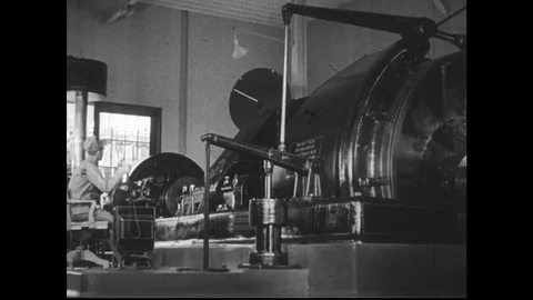 1940s: Mining machine in warehouse rotates. Tower above mine shaft. Ore lifted 動画素材 74522411