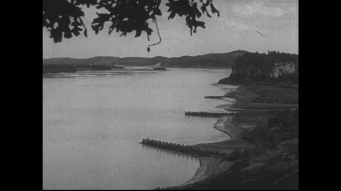 1940s: Missouri river next to factory. Train arrives at factory building. Lead Stock Footage
