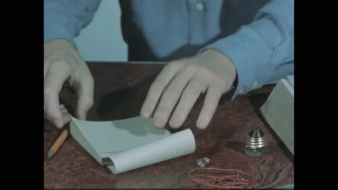 1940s: notepad and pencil on table. Hand crosses out notes on pad. Hand lines up Stock Footage 195118550