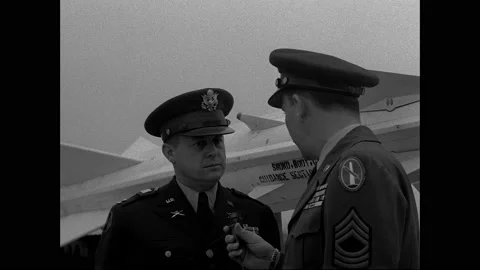 1940s: Officer interviews officer using microphone, standing next to rocket. 動画素材 158858030