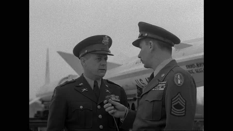 1940s: Officer interviews officer using microphone, standing next to rocket. 動画素材 158858083