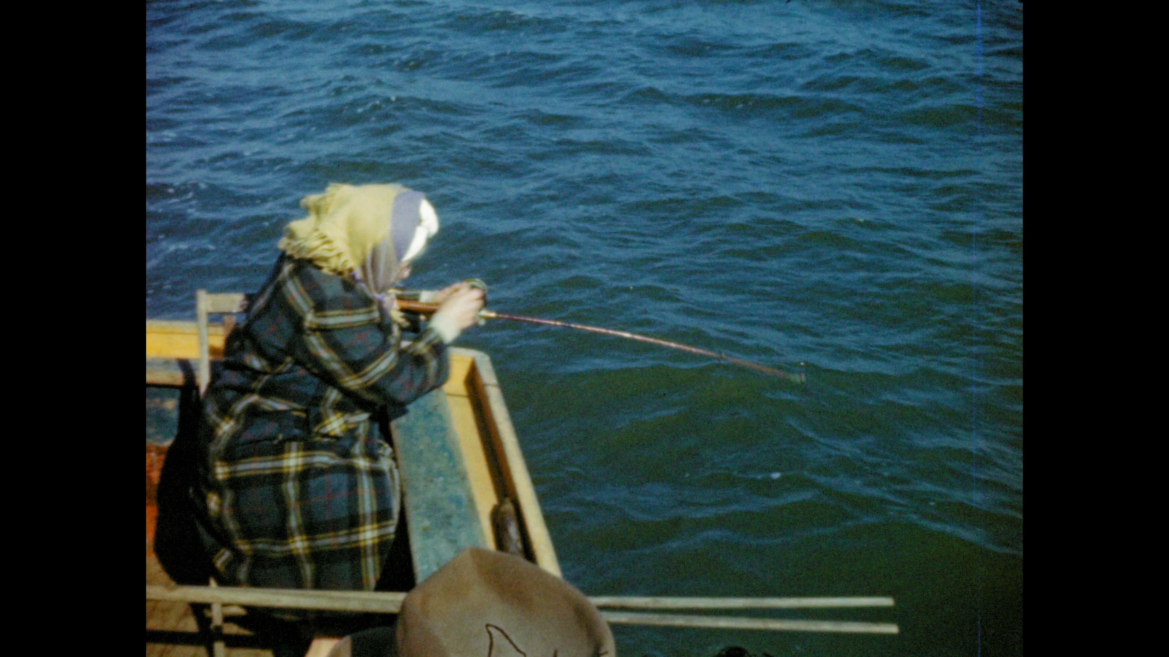 1940's: Woman unhooks flounder from fishing line; fisherman