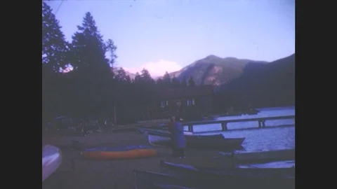 1940s: People walk along dock on mountain lake. Lake and tree-lined mountains. Stock Footage