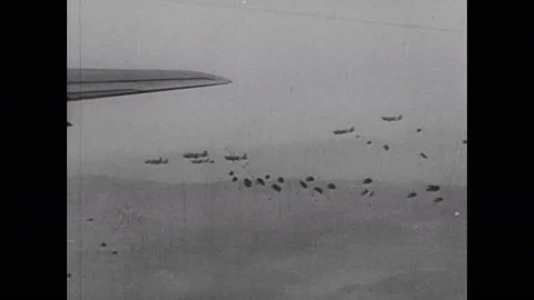 1940s: Planes fly through sky. Soldiers jump out of planes, deploy parachutes. Video stock 137411858
