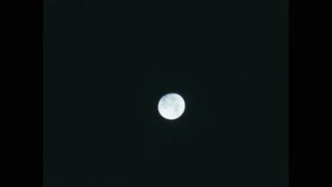 1940s: Point of light shines on a dark field. Full moon shines in night sky. Stock Footage 170459099