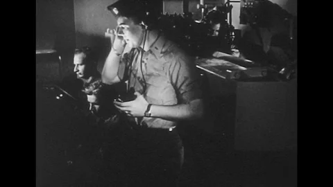 1940s: Radar operator speaks into headset / Soldier puts on microphone / Hand Stock Footage