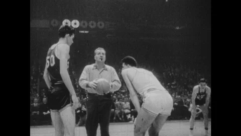 1940s: Referee throws up ball, men play basketball. Crowd watches people play Stock Footage 103327011