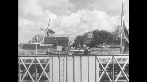 1940s: Sail boat moves away from docks. Windmills and canal docks. Sail boats Stock Footage