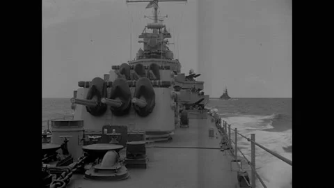 1940s: Sailor on deck of Navy ship stands with hands on signal light. Cannons on Stock Footage 158440888