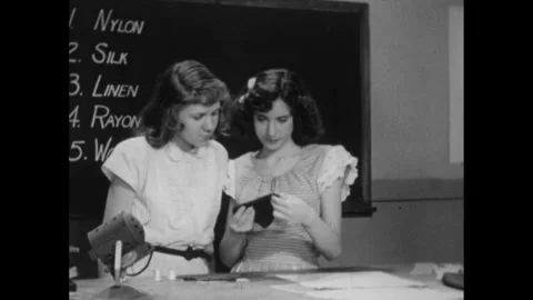 1940s: Students looking at different fabric patches. Linen swatch being creased. Stock Footage 261244543