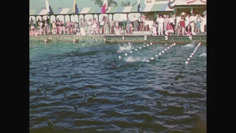 1940s: Swimmers race down outdoor pool lanes. Diver flips on board, dives. Young Stock Footage