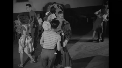 1940s: Teens dance on hall floor to music from jukebox. Choir rises in choir Stock Footage 156510447