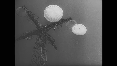 1940s: Title "U.S. Prepares More Paratroops for Battle". Parachutists jump from Stockbeeldmateriaal 141875194