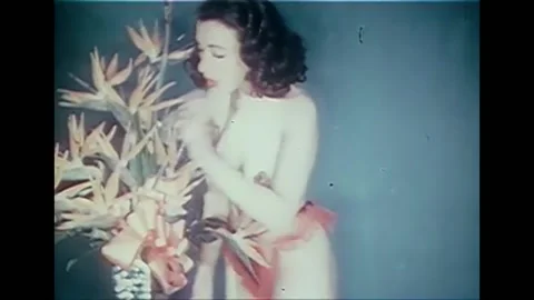 1940s - A topless model arranges a bouquet of Bird of Paradise. Stock Footage 170511655