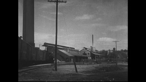 1940s: train arrives at lead smelter buildings. Man in carriage of train. Man in Stock Footage