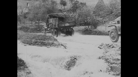 1940s: Trucks drive through flooded and muddy streets. Truck slides down icy Stock Footage