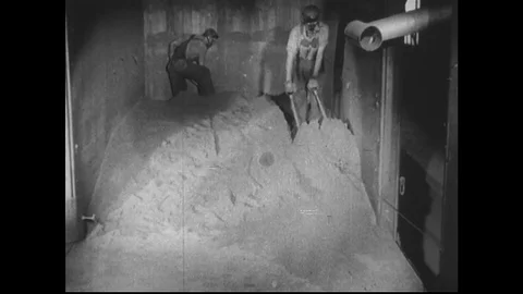 1940s: Two men load wheelbarrow with grain inside train carriage. Powder on Stock Footage