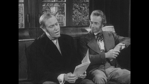 1940s: Two men sit on couch. Man reads poem from magazine. Men talk. Stock Footage 90828026