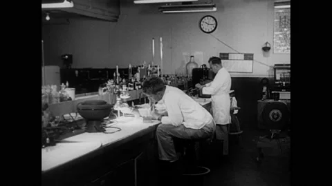 1940s: Two people conduct experiments in lab. Gauge, lab equipment, gauge, Vídeos de archivo 159390124