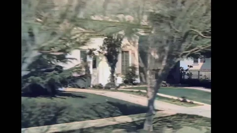 1940s - View from a car as it drives past houses and intersections in suburban Stock Footage 241798502