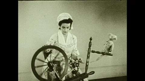 1940s: Woman in bonnet operates foot pedal spinning wheel. Woman operates wooden Stock Footage